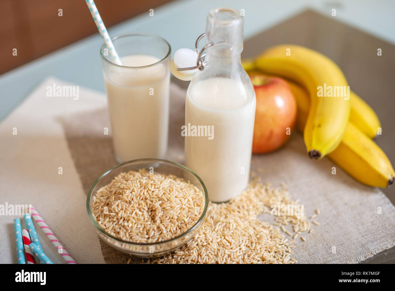 Le lait de riz dans une tasse en verre et des fruits avec des grains de riz sur la table dans la cuisine. Produit végétarien sain de régime Banque D'Images