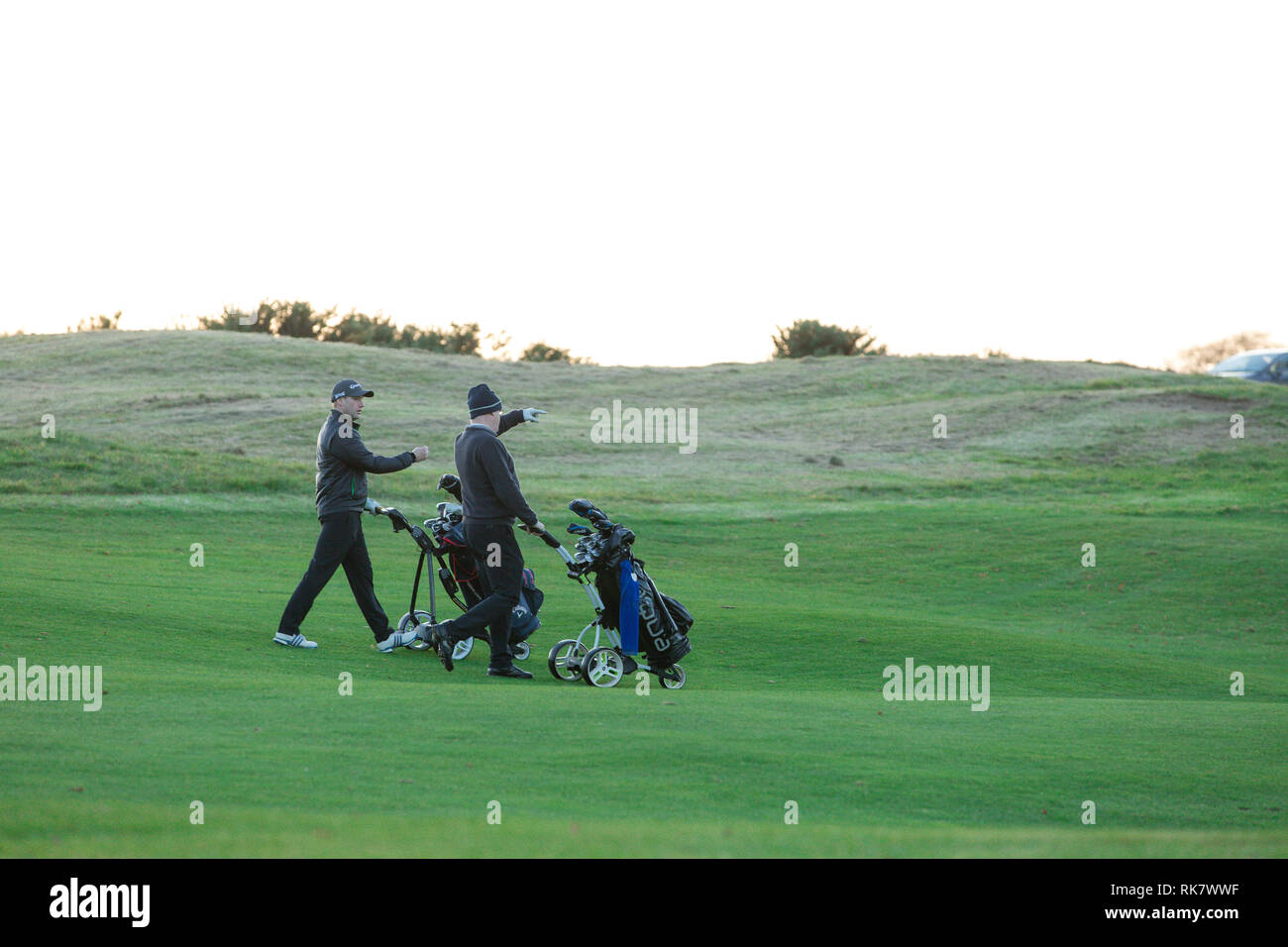 Deux hommes chariots manuels avec leurs sacs de golf à travers verts sur le carton House Golf à Maynooth, comté de Kildare, Irlande Banque D'Images