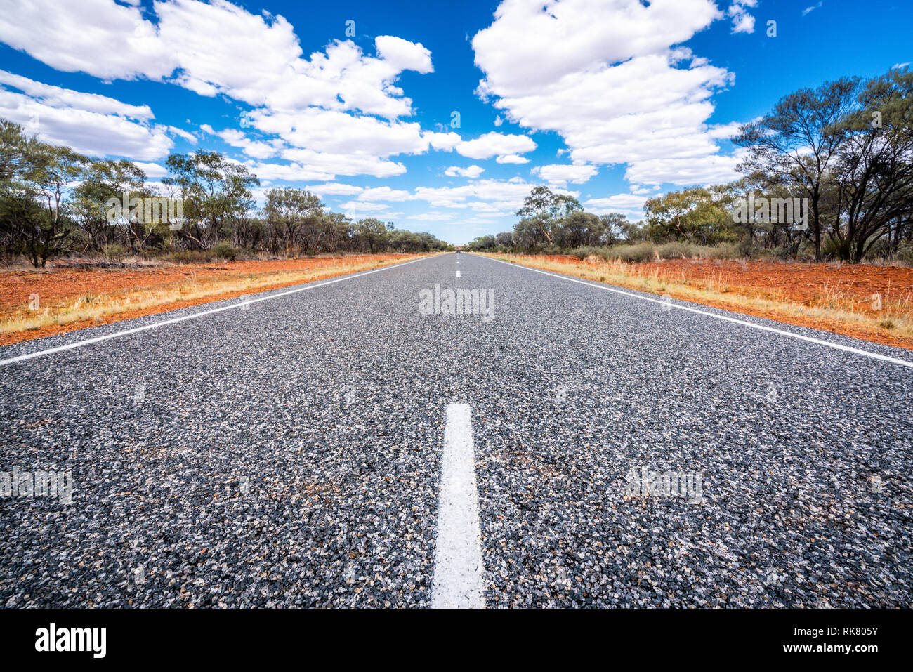 Route droite avec des lignes blanches au milieu du centre rouge de l'outback Australie NT Banque D'Images