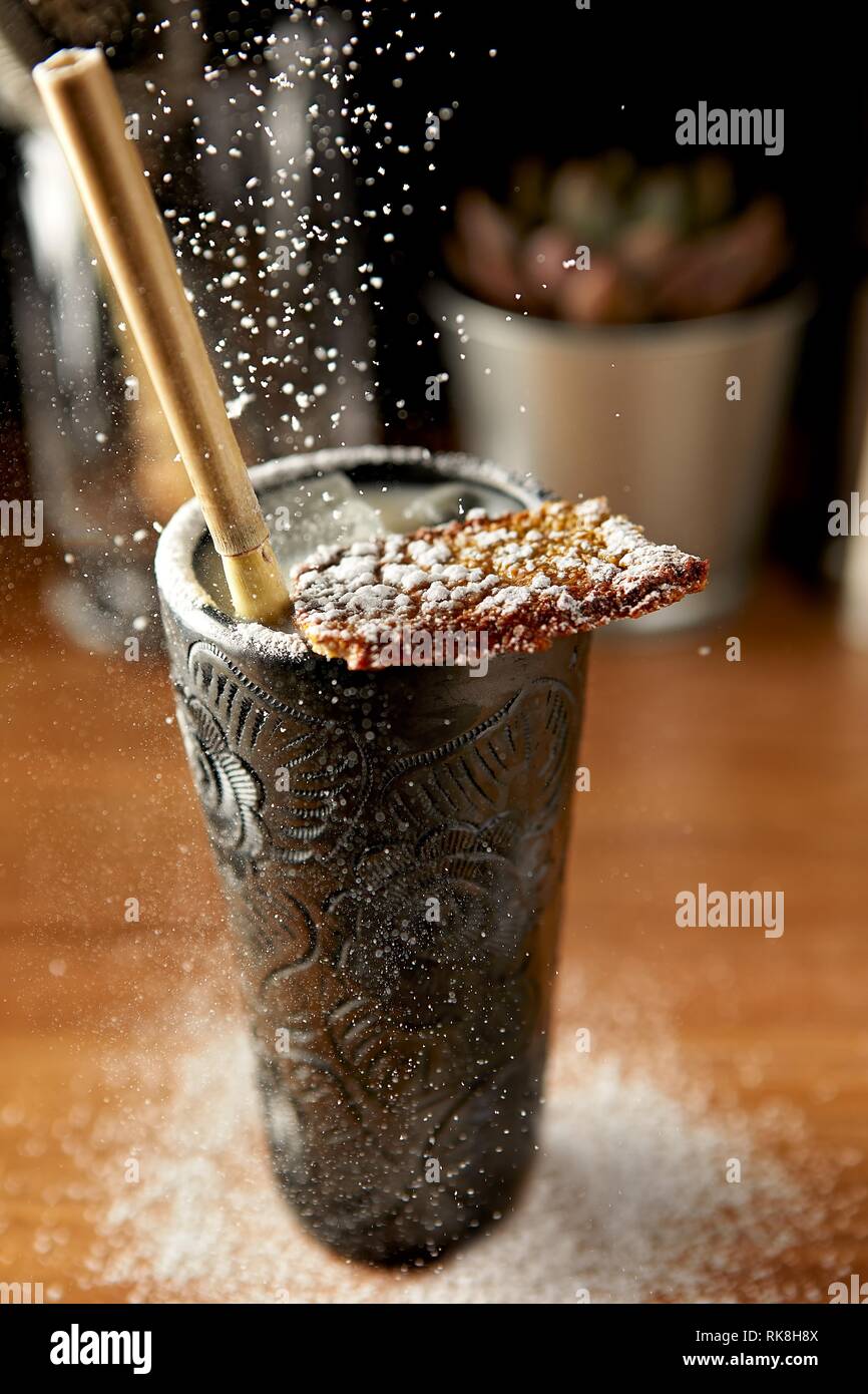 Verser du sucre glace sur un grand cocktail au bar compteur Banque D'Images