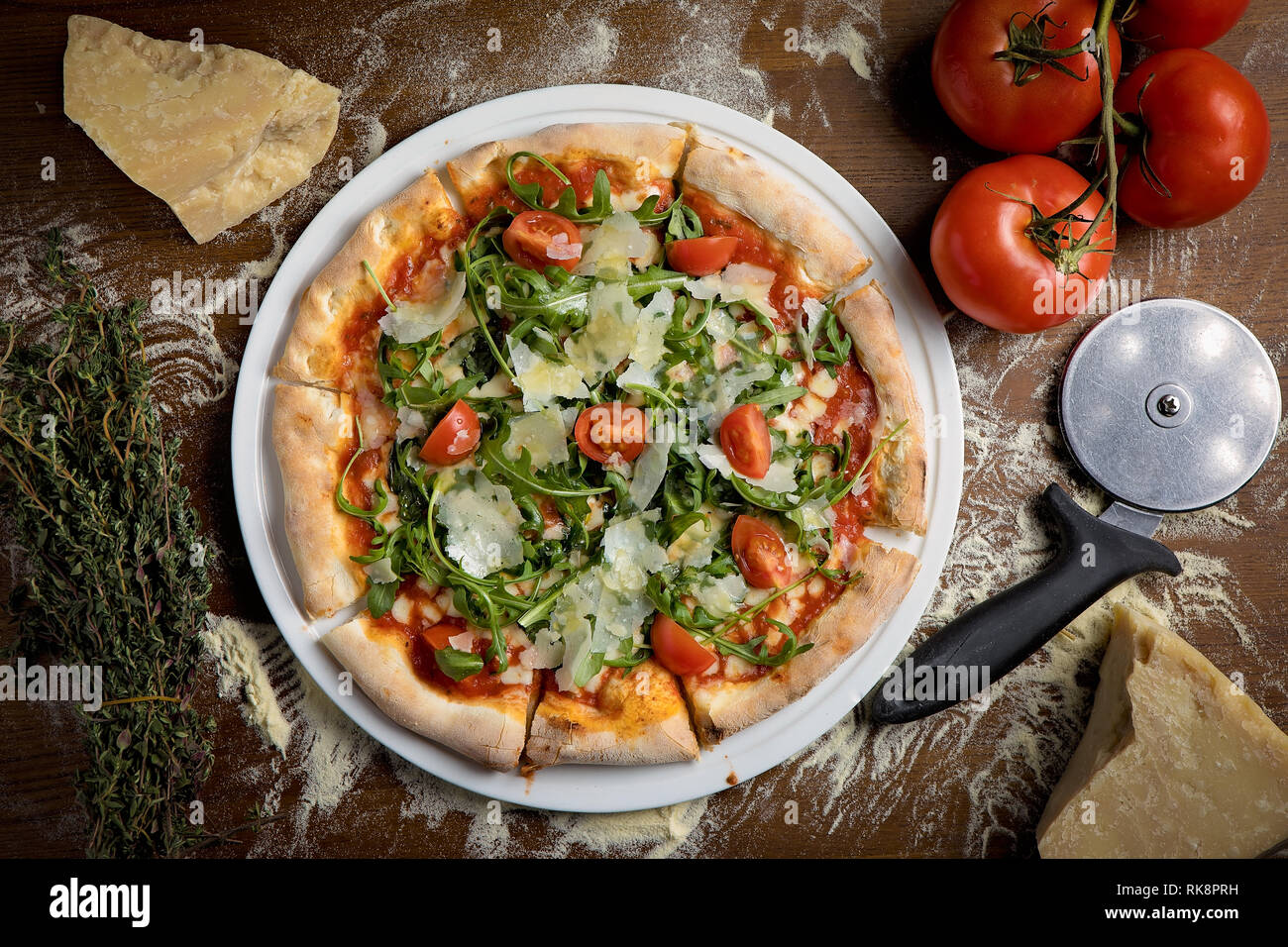 Photo de haut en bas d'une pizza végétarienne à croûte mince avec tomate, parmesan, roquette sur une base de tomate Banque D'Images