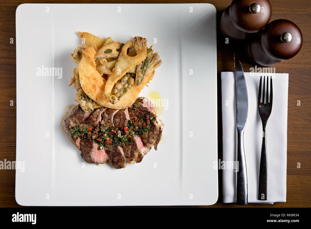 Photo de haut en bas d'un steak juteux servi avec une sauce et quelques légumes frits. Banque D'Images