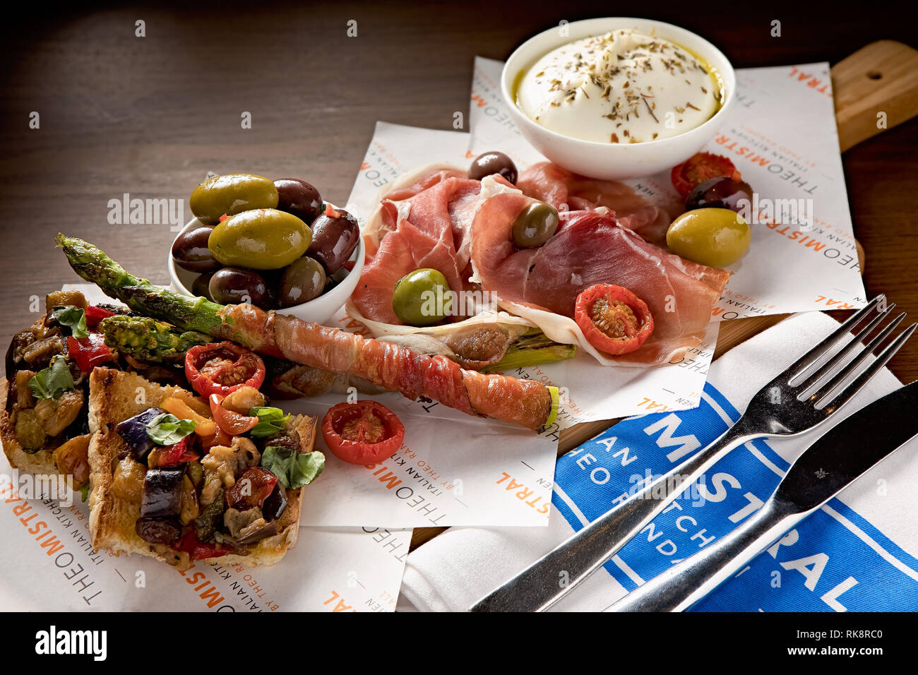 Sélection fraîche d'antipasti italiens, tels que des olives, du pain grillé aux légumes, du fromage crémeux et du jambon fumé Banque D'Images
