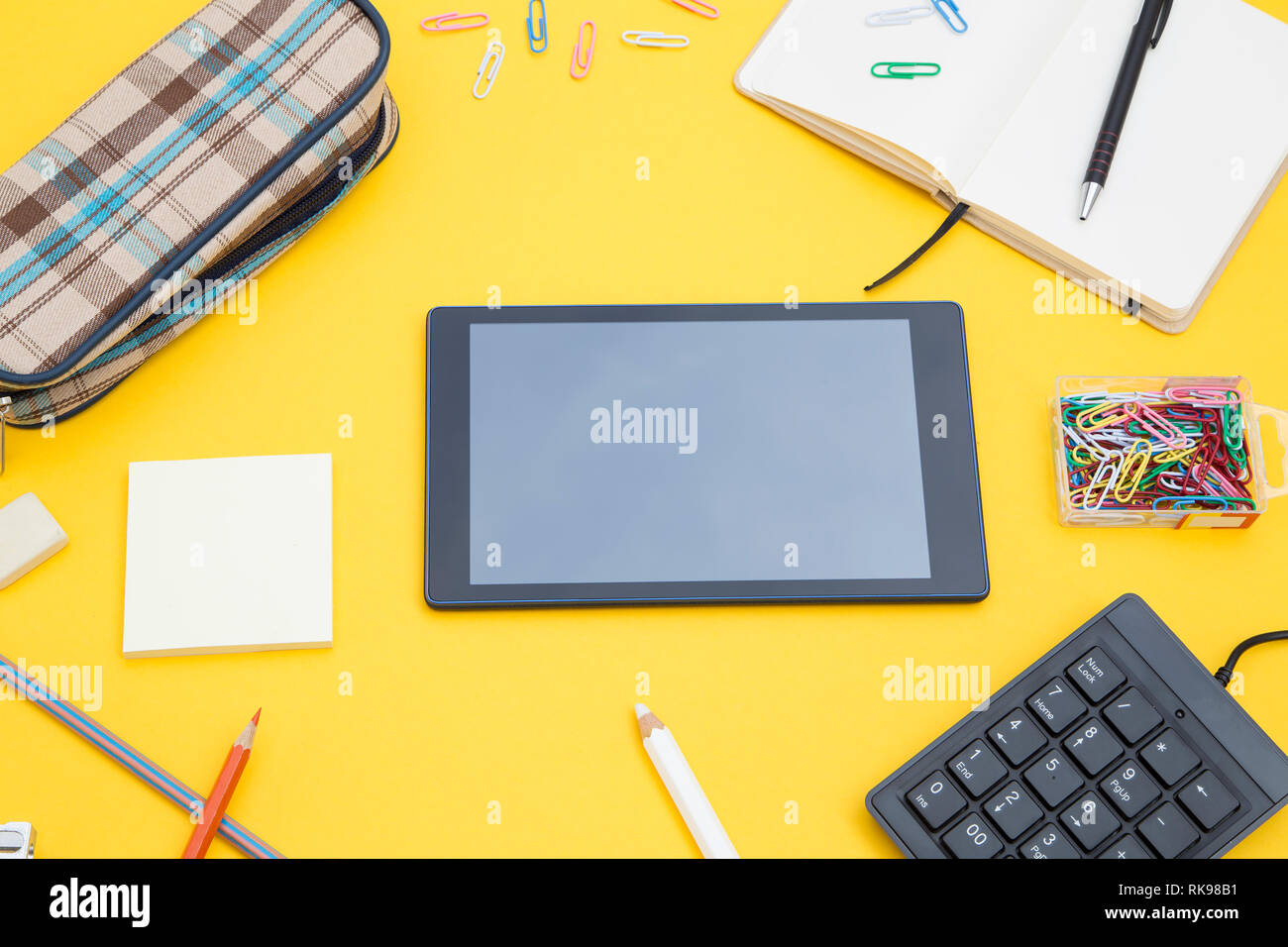 Les fournitures scolaires avec une tablette graphique sur fond jaune Banque D'Images