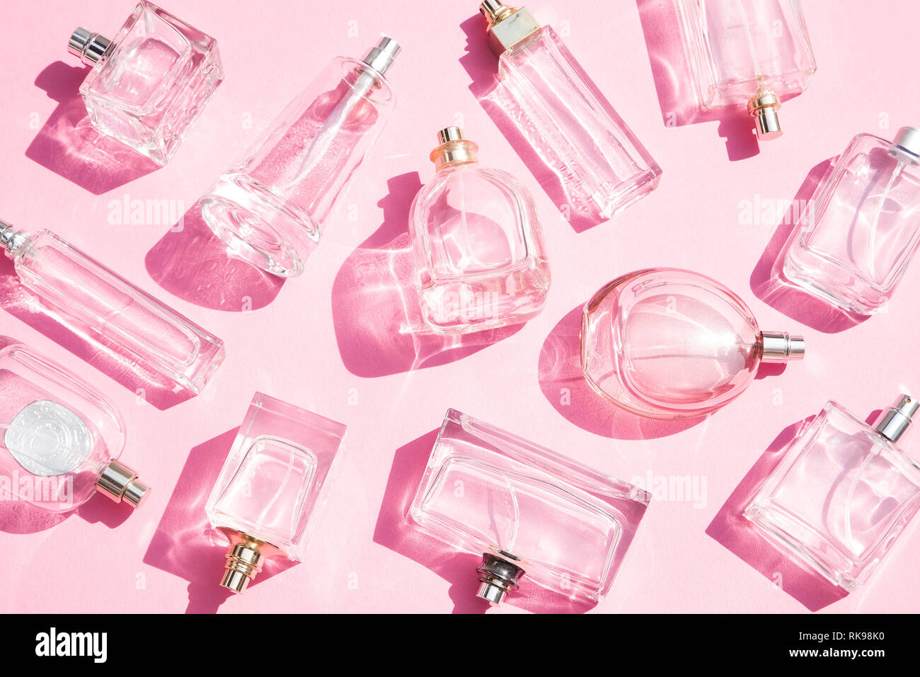 Flacons de parfum sur fond rose Banque D'Images