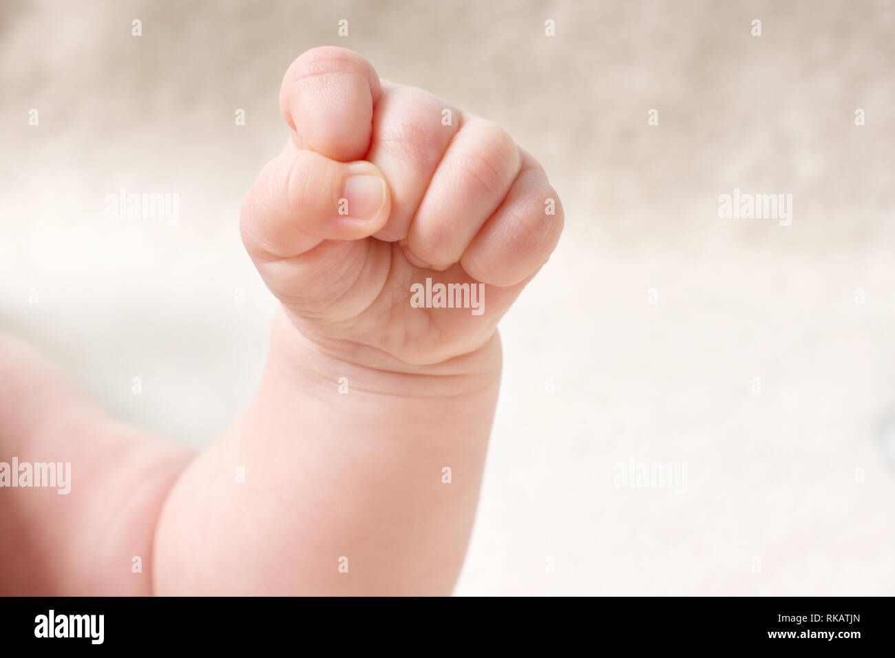Petit bébé dans la main serra le poing. Petite new born baby's arm gros plan sur fond clair Banque D'Images