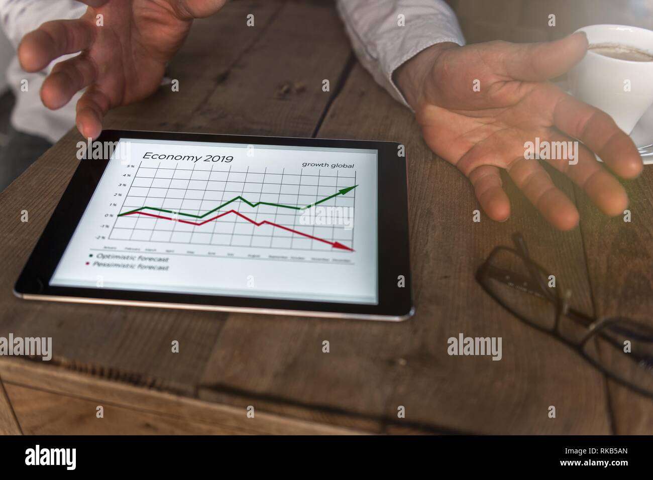 Une tablette avec l'information économique est sur la table. Les mains d'un homme sont visibles. Banque D'Images