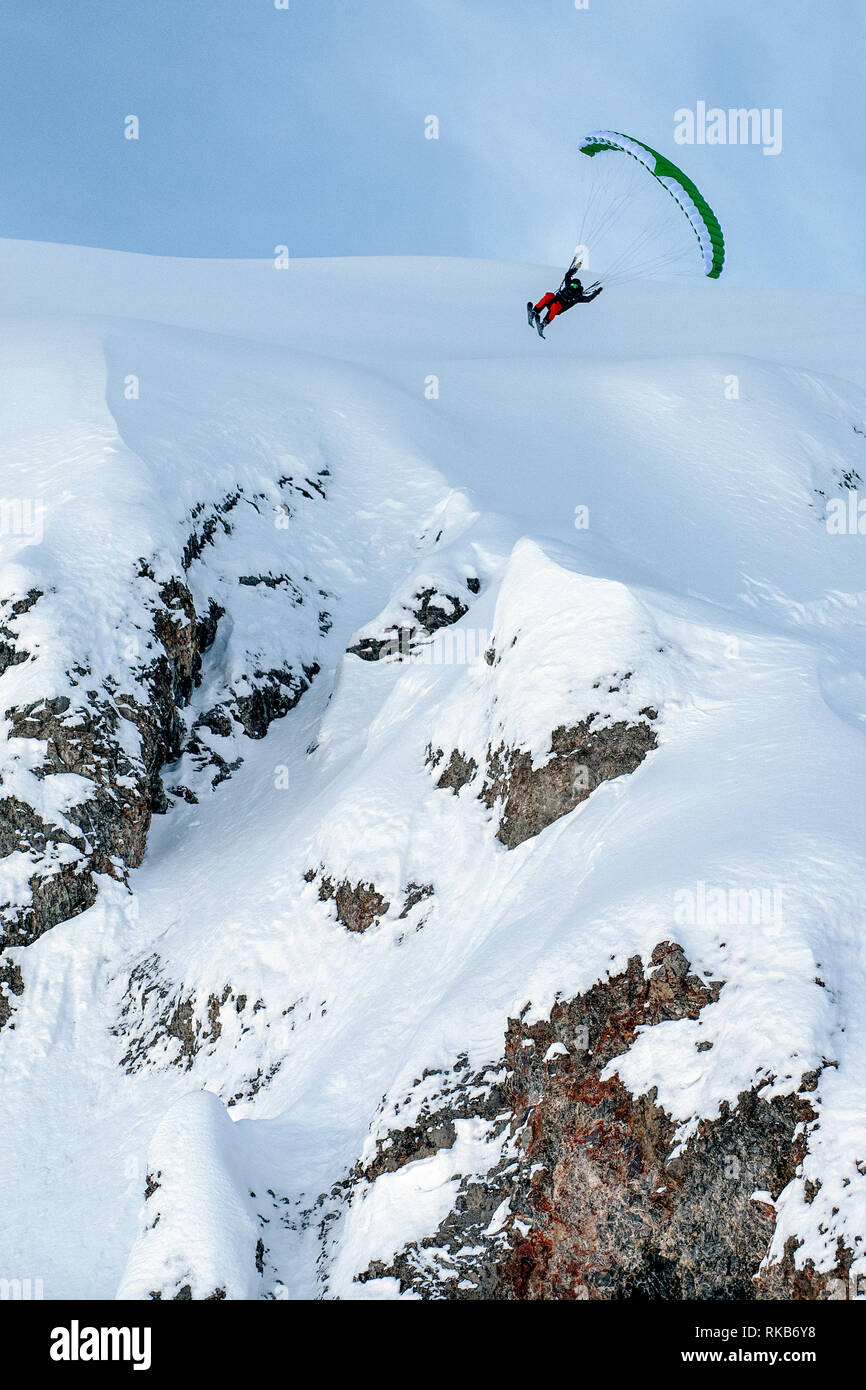 Speed-flying dans la station alpine de Courchevel. Un homme vole à l'aide d'un speed-flying wing sur des skis d'une falaise sur la neige. Banque D'Images