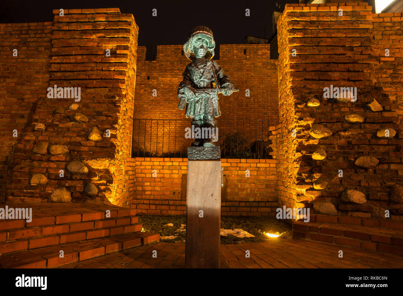 Petite statue d'insurgés contre l'ancien mur de la ville la nuit à Varsovie, Pologne. Monument aux enfants soldats qui se sont battus et sont morts au cours de la Warsaw Uprisin Banque D'Images