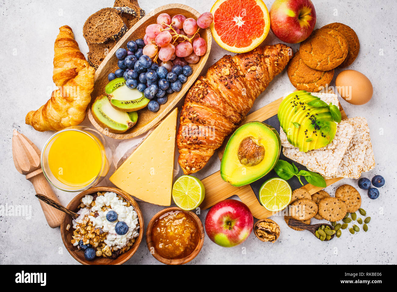 Petit-déjeuner sain et équilibré sur un fond blanc. Muesli, jus de fruits, des croissants, du fromage, des biscuits et des fruits, vue du dessus. Banque D'Images