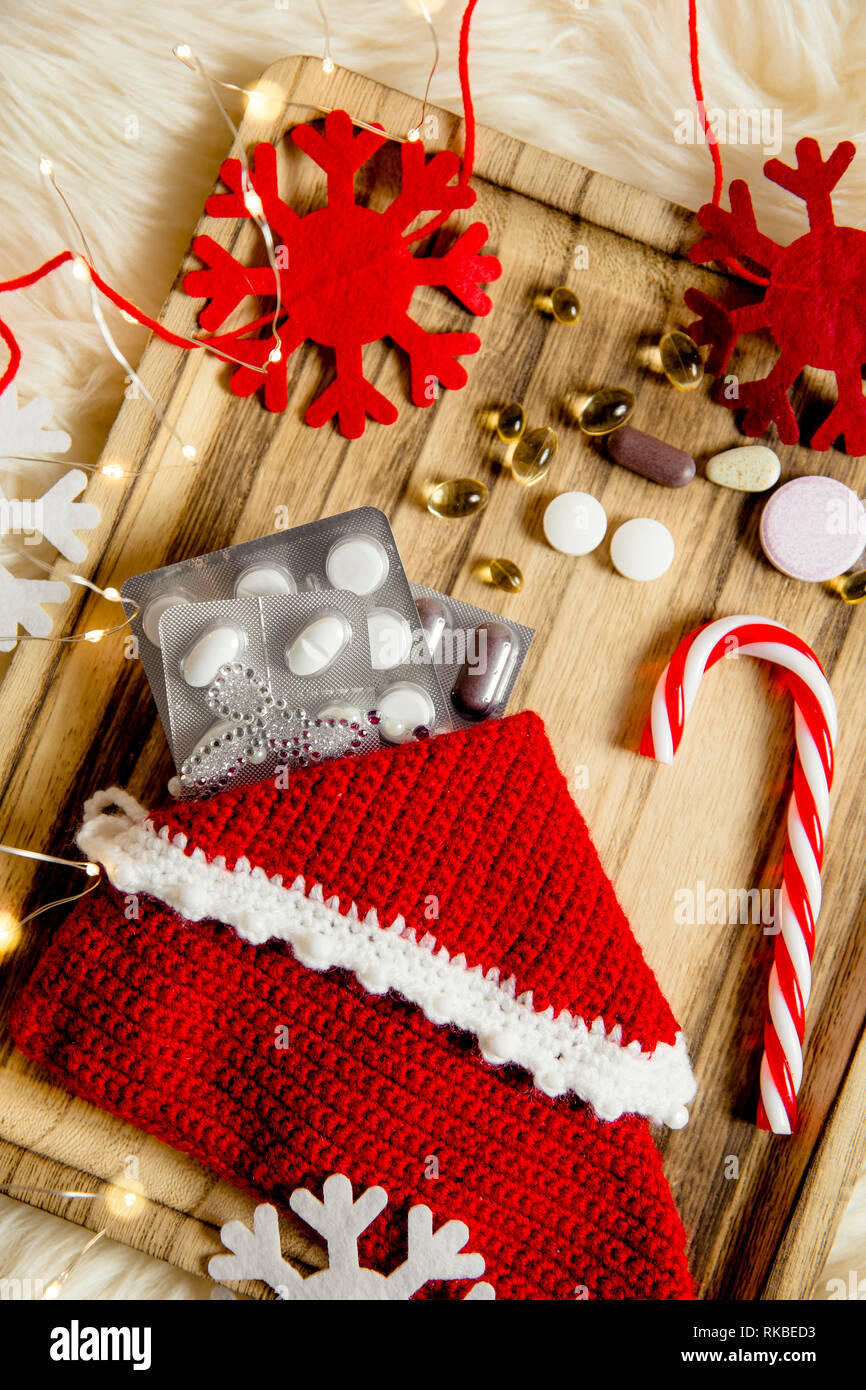 Vue de dessus de différentes pilules de vitamines comme cadeau de Noël dans la pantoufle de Jersey sur vintage plateau en bois avec impression flocons comme décoration. Idée cadeau conc Banque D'Images