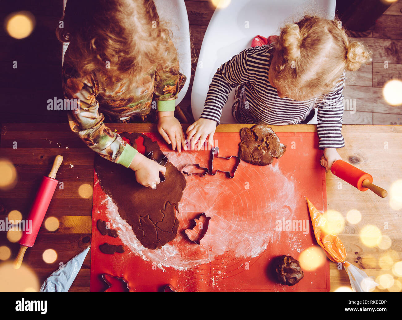Vue de dessus deux jeunes filles soeurs rouler la pâte et faire sweet gingerbread cookies croustillants. Plaisir d'hiver noël famille saisonniers activité. Banque D'Images