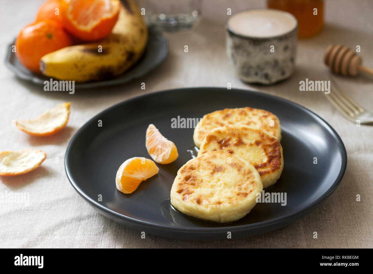 Petit déjeuner végétarien de quark des crêpes au miel, de fruits et de café avec du lait. Style rustique. Banque D'Images