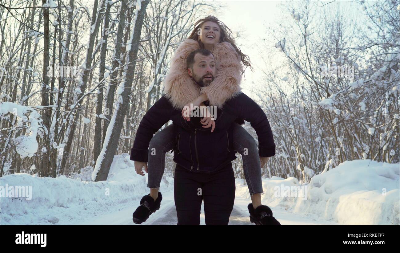 Beau young Caucasian couple amoureux les gens sur une date dans le parc d'hiver. Le mec est porteur d'une jeune fille sur ses épaules dans un parc d'hiver. Valentine's day Banque D'Images