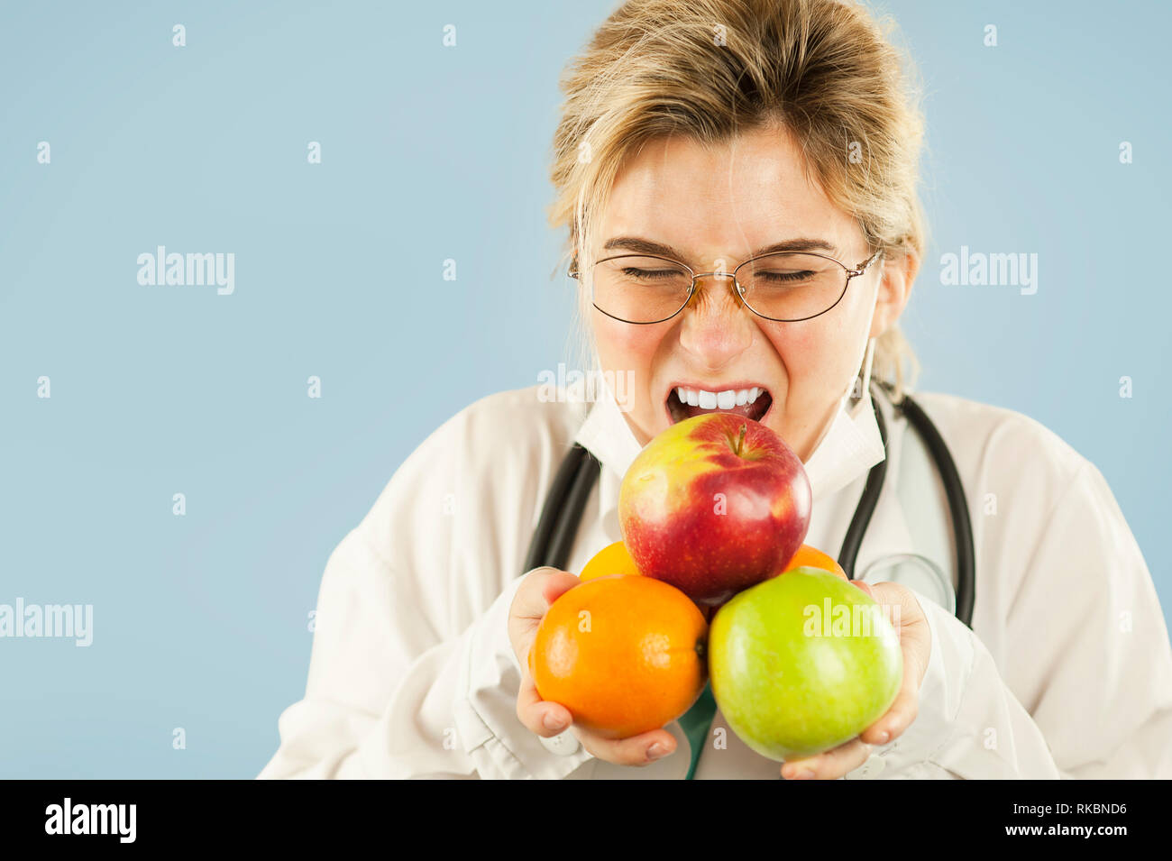 Belle fille médecin nutritionniste avec fruit dans la main sur fond isolé bleu. Concept de saine alimentation Banque D'Images