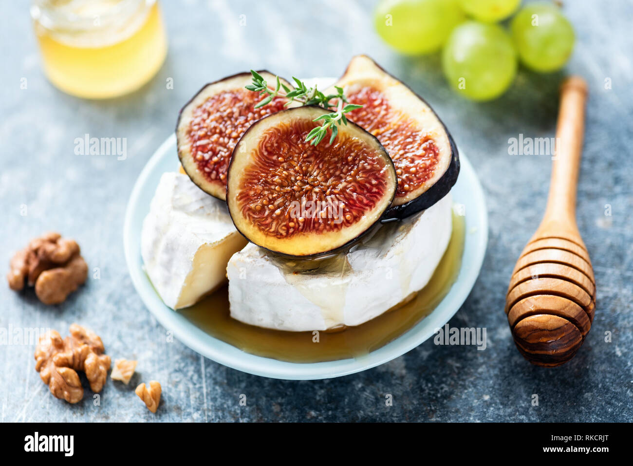 Le Camembert ou le brie aux figues, miel, raisins sur fond bleu Banque D'Images