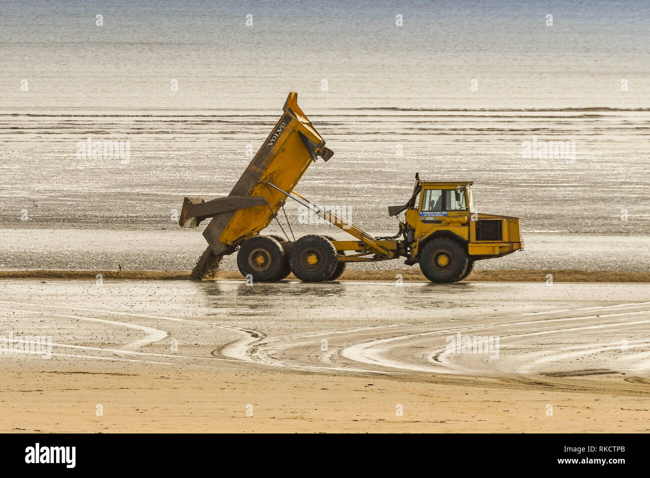 SWANSEA, Pays de Galles - Octobre 2018 : Truck dumping un plein chargement de sable sur la plage à marée basse à Swansea. Le sable avait été soufflé à l'arrière de la plage Banque D'Images