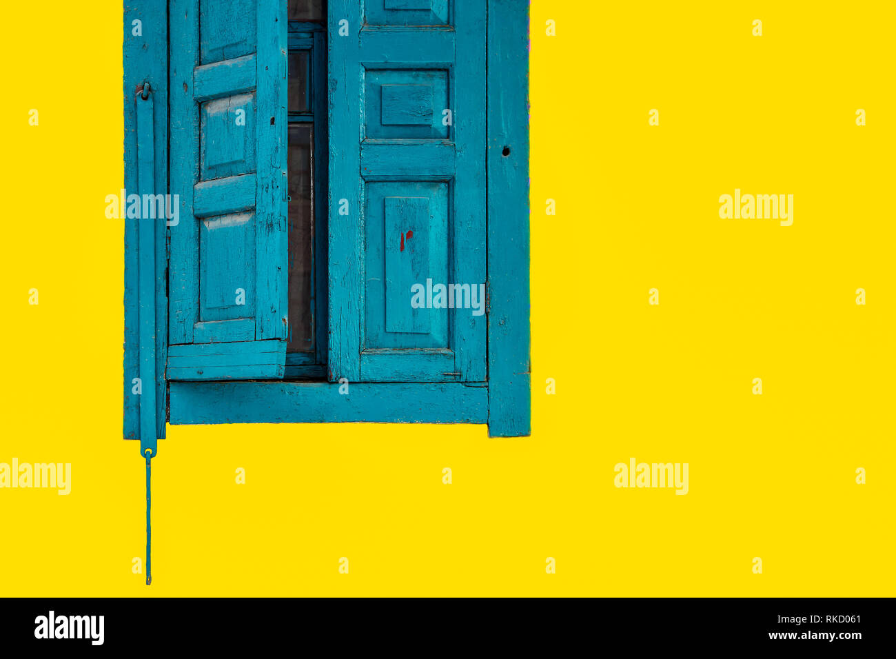 Les vieilles fenêtres, rideaux bleus sur fond jaune Banque D'Images