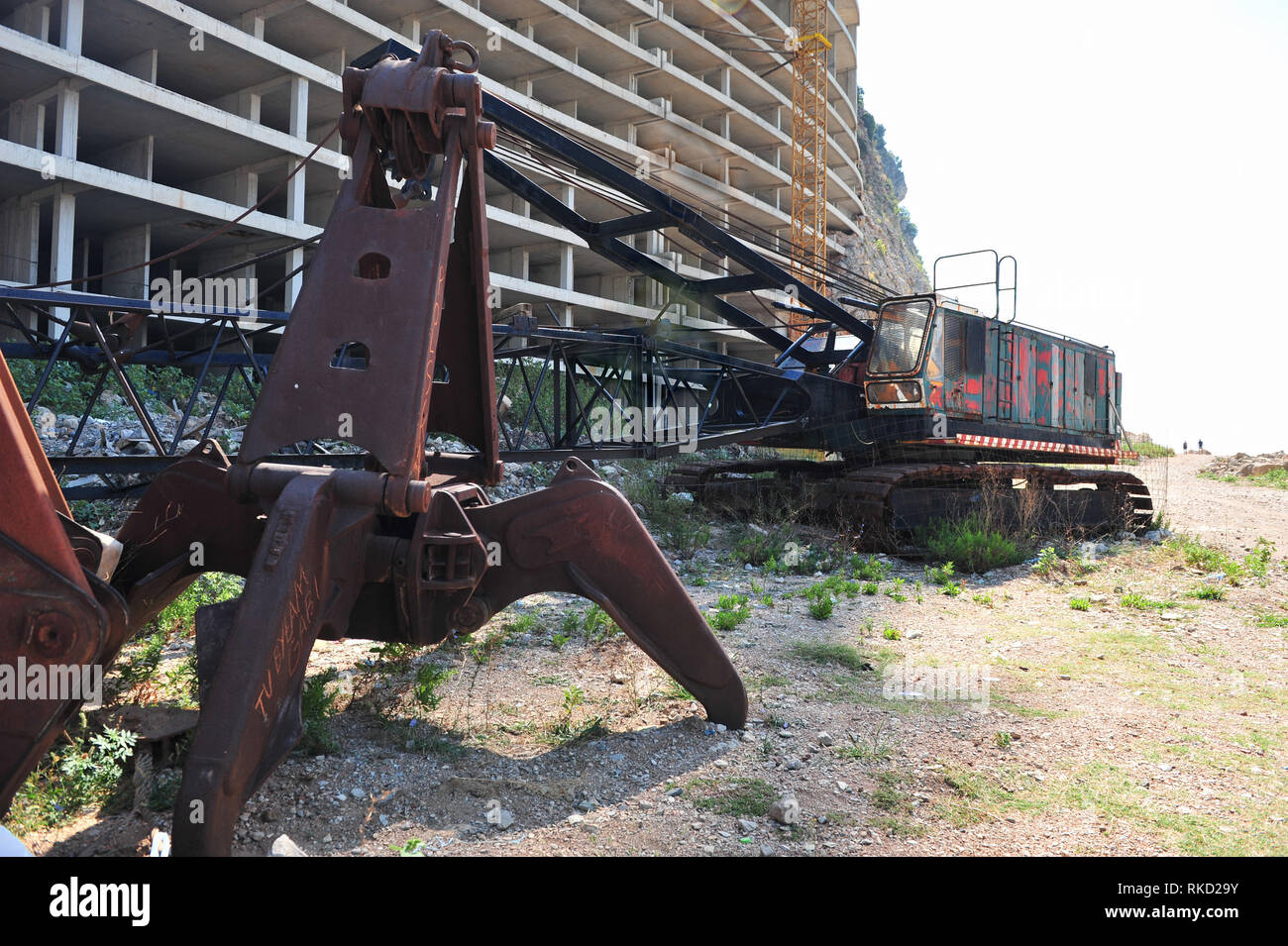 Grue abandonnée en face de l'hôtel inachevé au Monténégro. Machine rouillée et vide immeuble abandonné. Banque D'Images