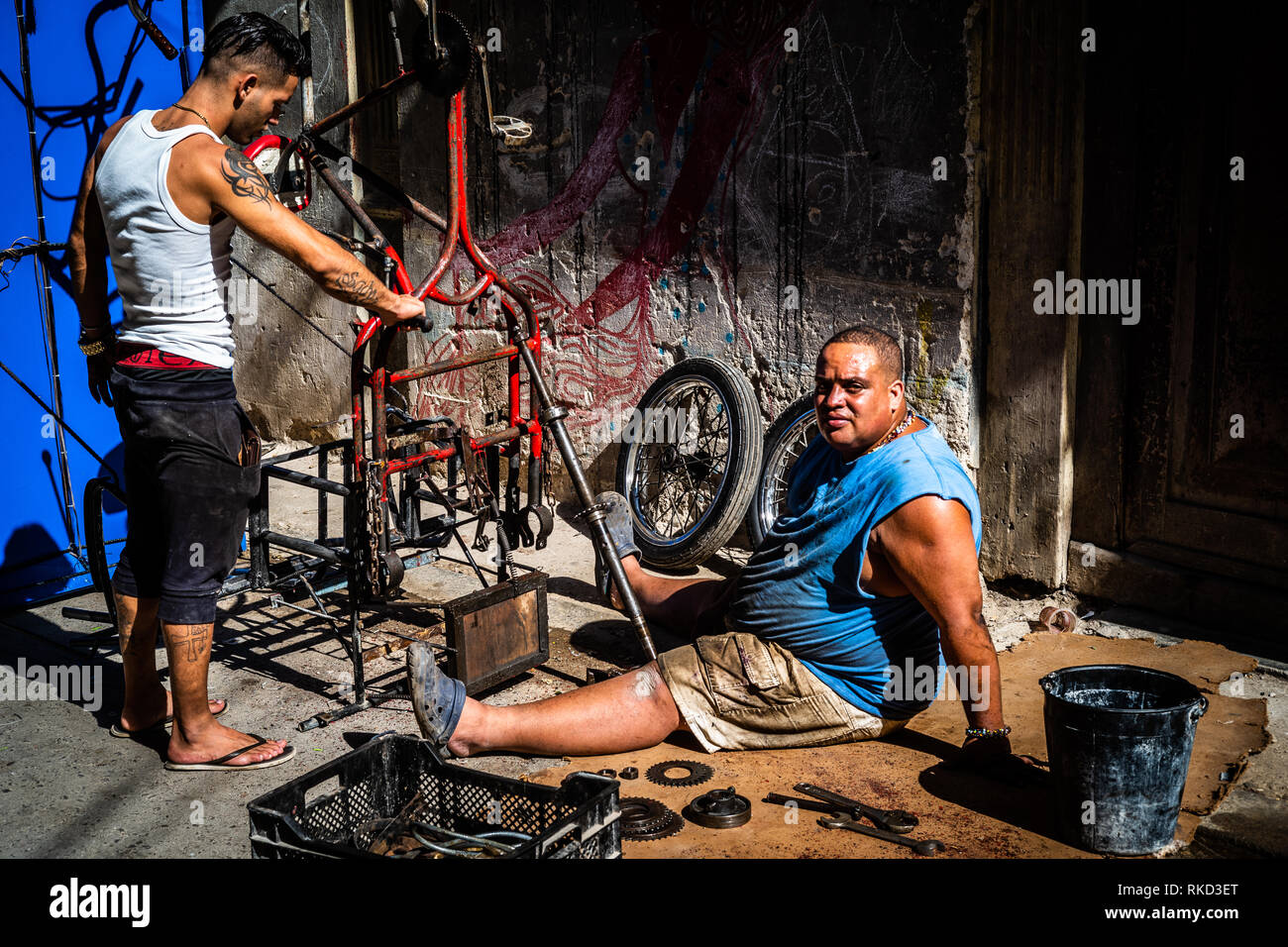 Deux mecs la réparation d'un vélo dans les rues de La Havane à Cuba. Banque D'Images