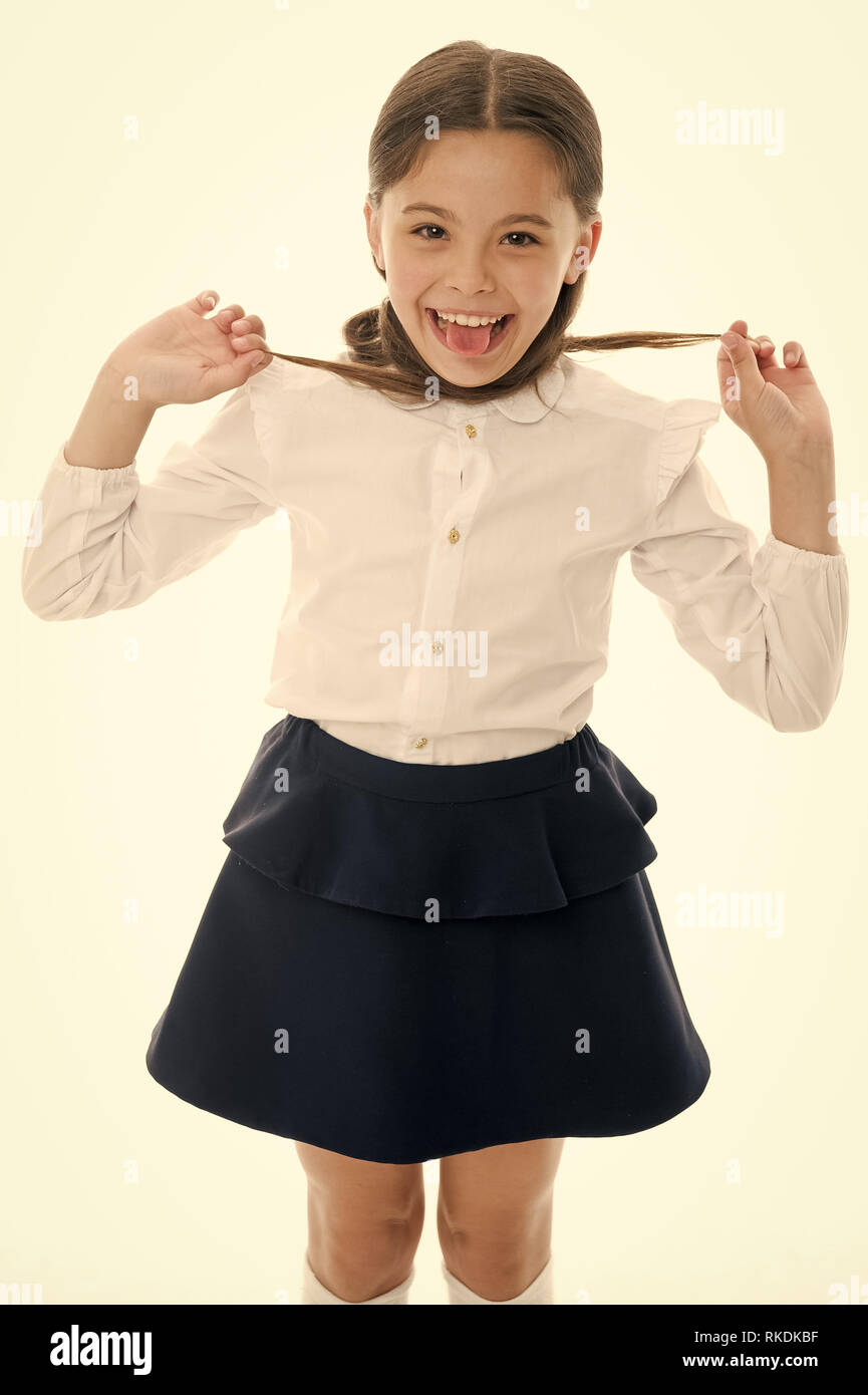 Happy girl show langue isolé sur blanc. Enfant grimace avec de longs cheveux de brunette. La mode écolière. Salon de beauté. Pousser vos cheveux tout le chemin. Banque D'Images