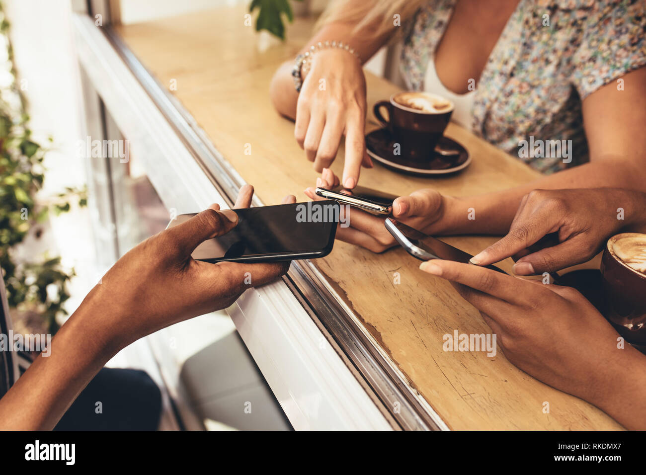 Cropped shot de jeunes reliant leurs appareils au coffee shop. Close up de vos amis à l'aide de Wi-Fi pour connecter les téléphones portables. Banque D'Images