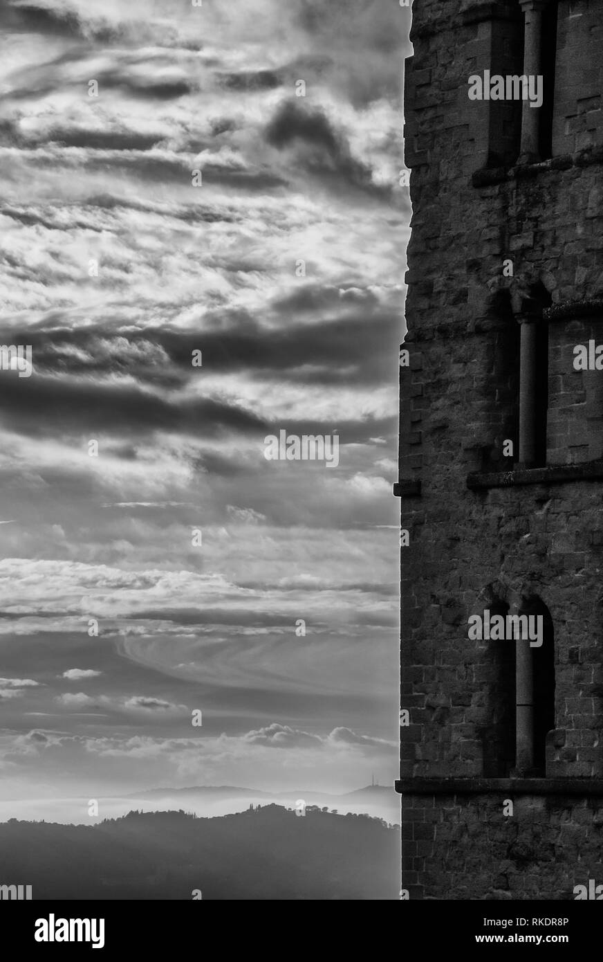Clocher médiévale romane avec coucher de soleil nuages et hill enveloppé dans la brume à Arezzo (noir et blanc avec copie espace) Banque D'Images