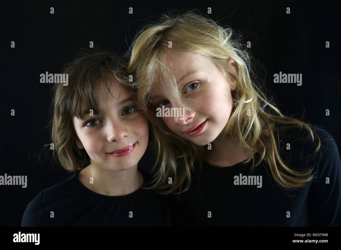 Deux jeunes filles en mettant leurs têtes ensemble pour un portrait sur un fond noir Banque D'Images