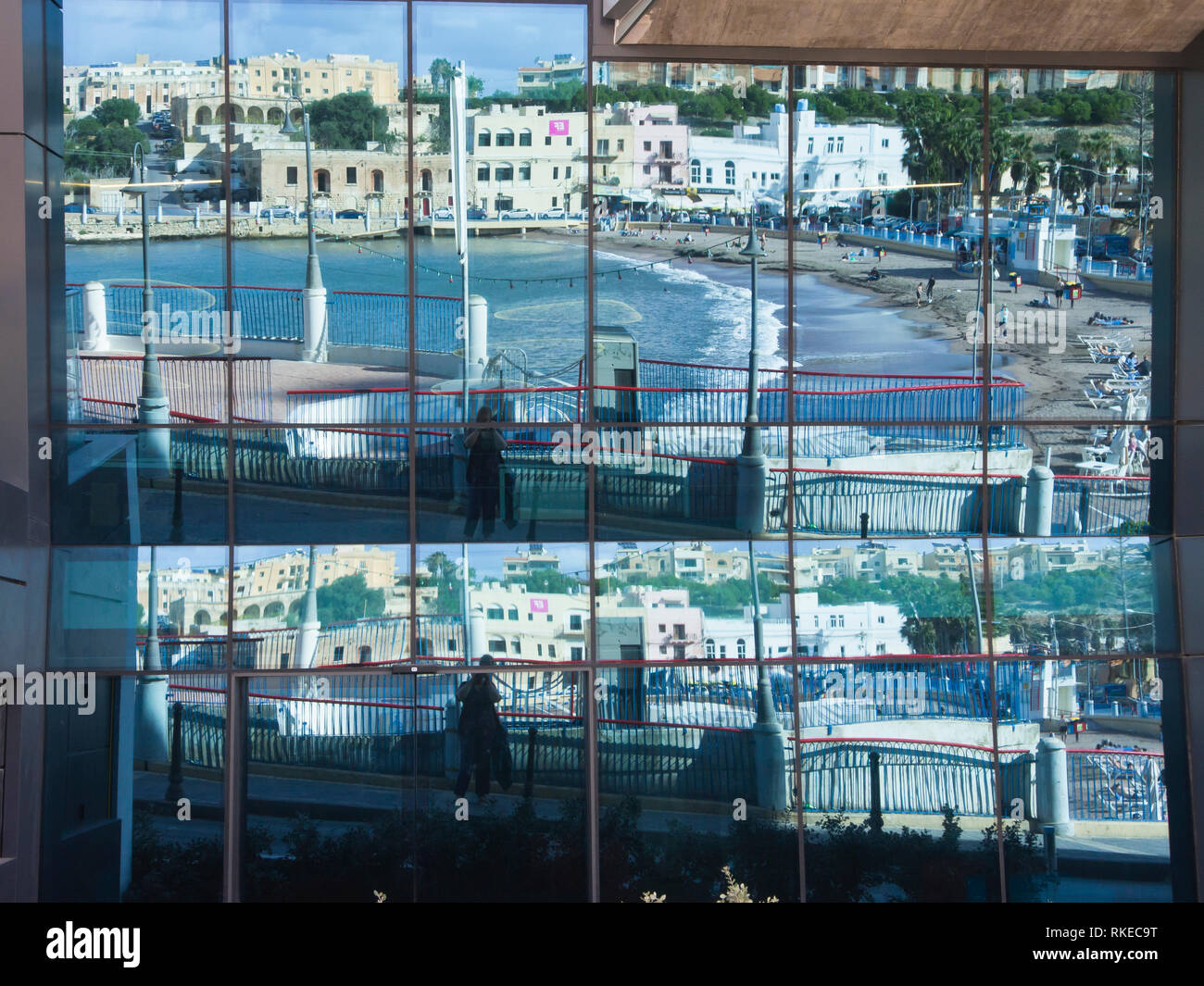 St George's Bay, San Ġiljan, Malte une plage de sable abritée près de La Valette, reflétée dans un motif en mosaïque les fenêtres d'un édifice commercial Banque D'Images