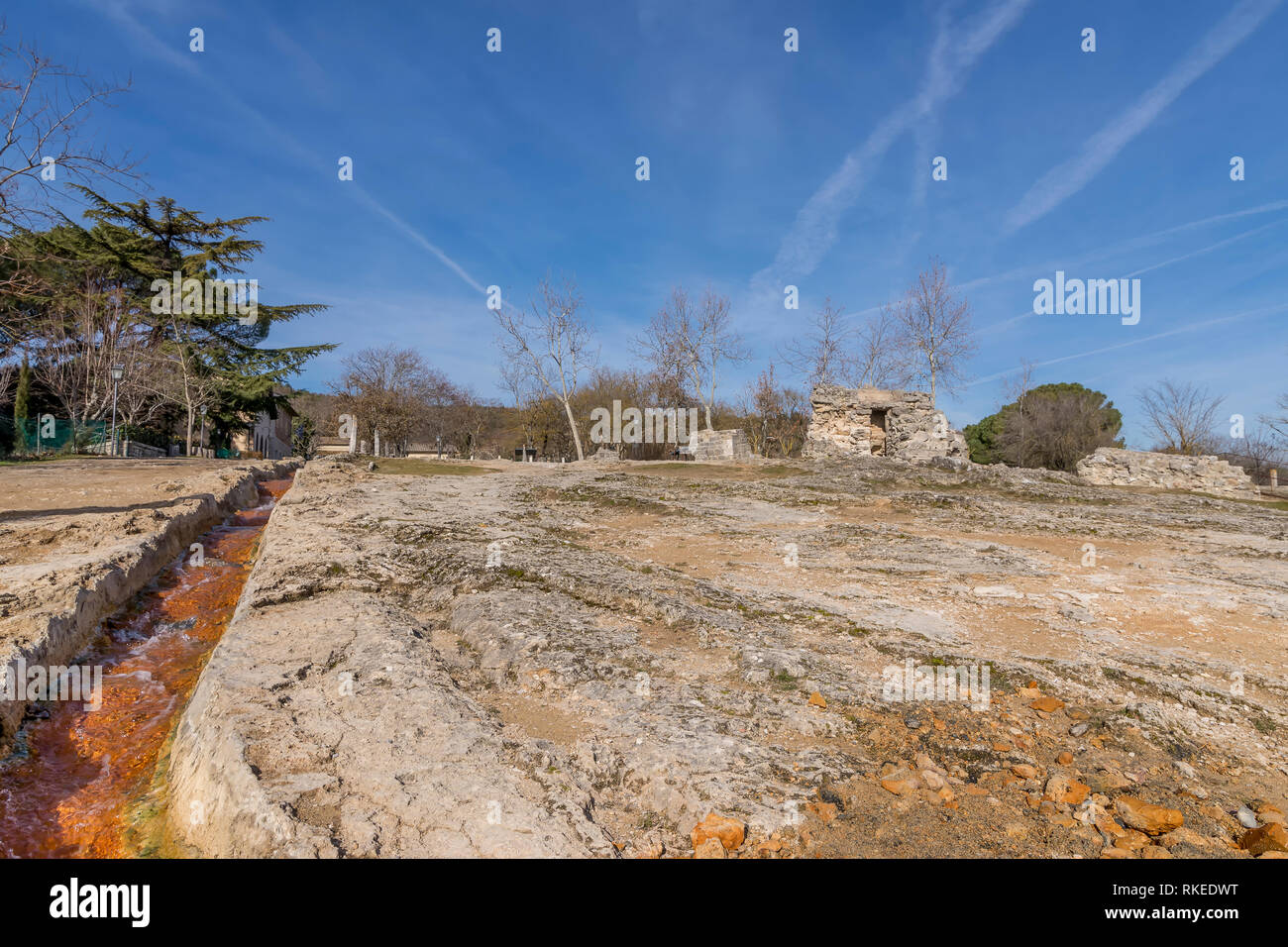 L'eau thermale coule dans la roche du Bagno Vignoni mill park sous un ciel magnifique, Toscane, Italie Banque D'Images