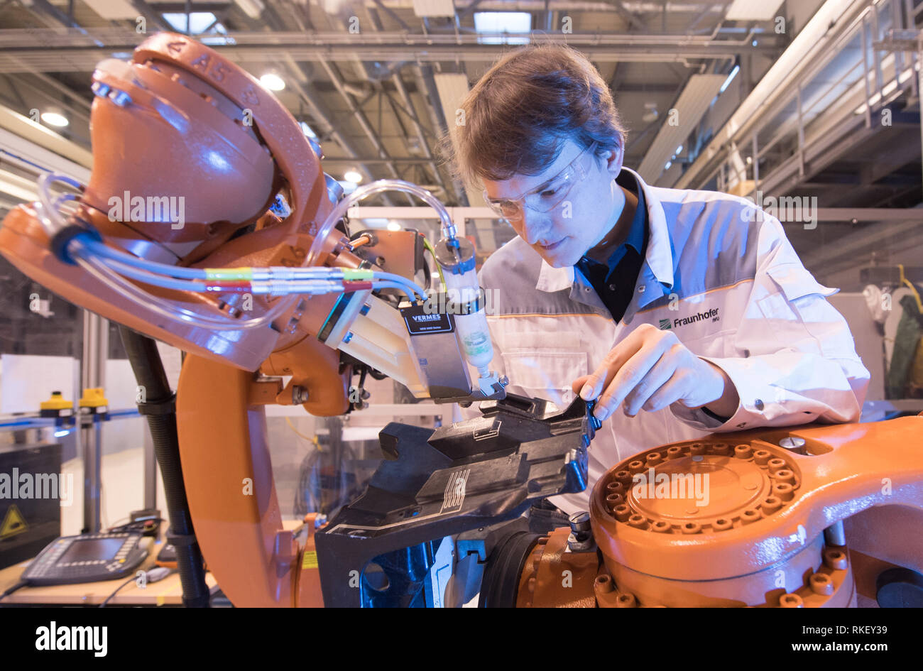 11 février 2019, Saxe, Dresde : Johannes Weber, assistant scientifique, inspecte un robot industriel pour la fonctionnalisation de composants 3D à l'occasion de l'événement fondateur de l'Institut Fraunhofer pour les systèmes de production Centre cognitif. Le centre est d'être exploité en collaboration avec l'Université technique de Dresde, avec un accent sur la recherche sur l'intelligence artificielle aux emplacements Chemnitz et Dresde. Photo : Sebastian Kahnert/dpa Banque D'Images