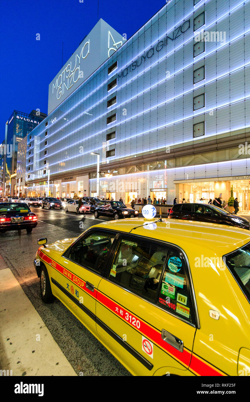 Tokyo Ginza, l'heure bleue. Taxi jaune en premier plan avec l'énorme magasin Matsuya illuminé de l'autre côté de la rue. La nuit. Banque D'Images