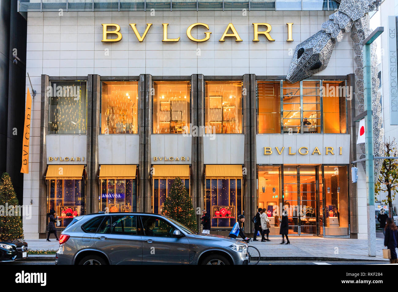 Tokyo, Ginza. L'Heure Bleue. Magasin Bvlgari illuminé avec châssis serpent enroulé autour. La lumière de Noël. Premier plan, les gens sur passage piétons. Banque D'Images