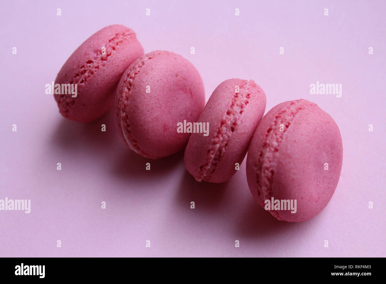 Quatre macarons rose sur un fond rose. Banque D'Images