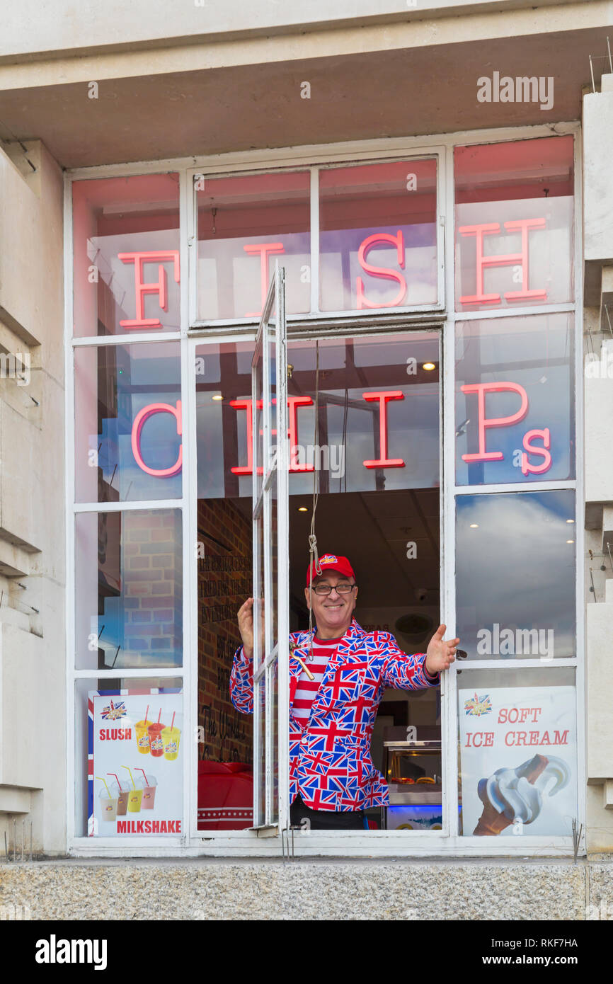 Dans l'homme Union Jack jacket regardant par la fenêtre Fish & Chips à Londres en février Banque D'Images