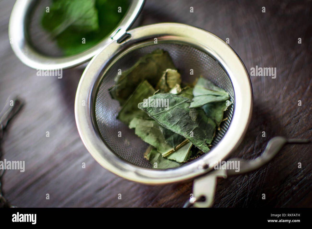 Metal thé avec les feuilles séchées de thé vert et de menthe fraîche sur un fond en bois brun foncé Banque D'Images