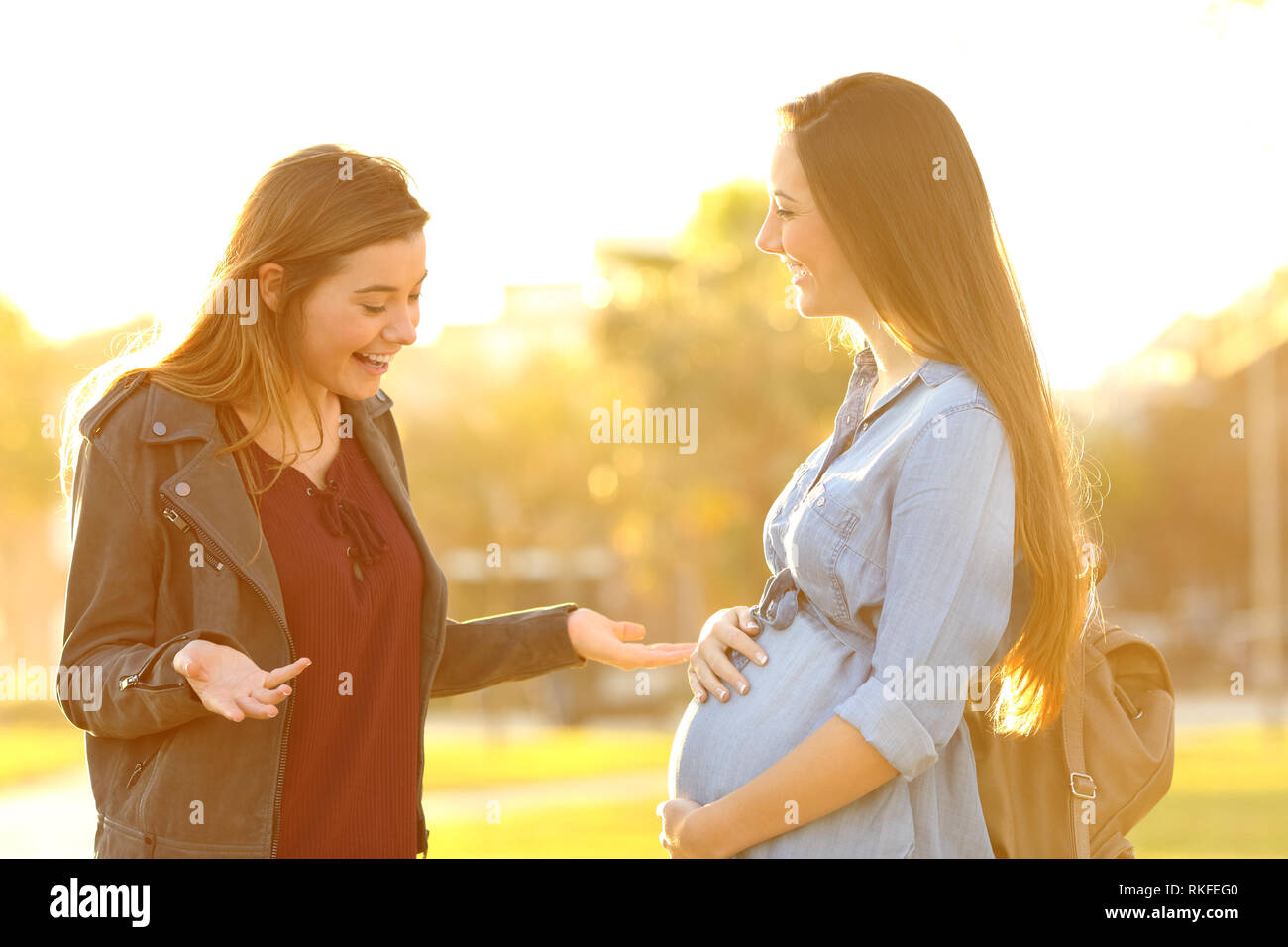Surpris femme enceinte réunion ami dans un parc au coucher du soleil Banque D'Images