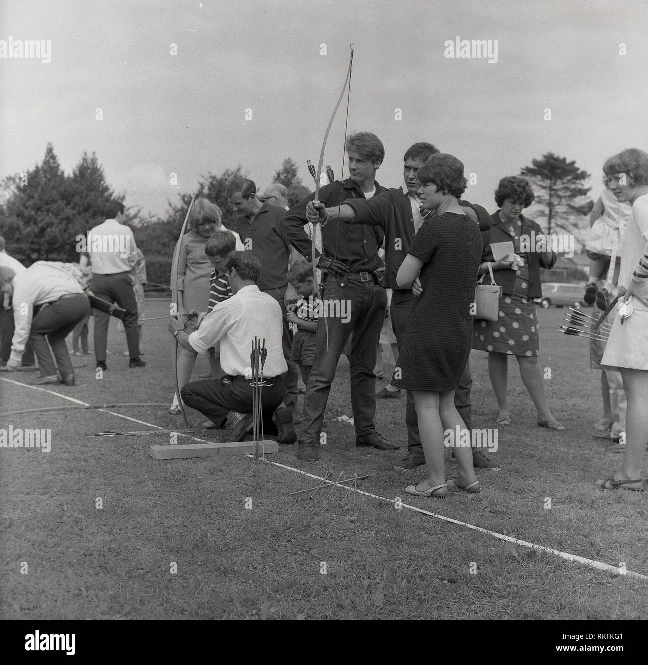 1967 Gojomo, fête du village, les personnes ayant un rendez-vous au tir à l'ARC, le sport ou la pratique de compétences, lancer des flèches sur une cible en utilisant un arc, Buckinghamshire, England, UK Banque D'Images