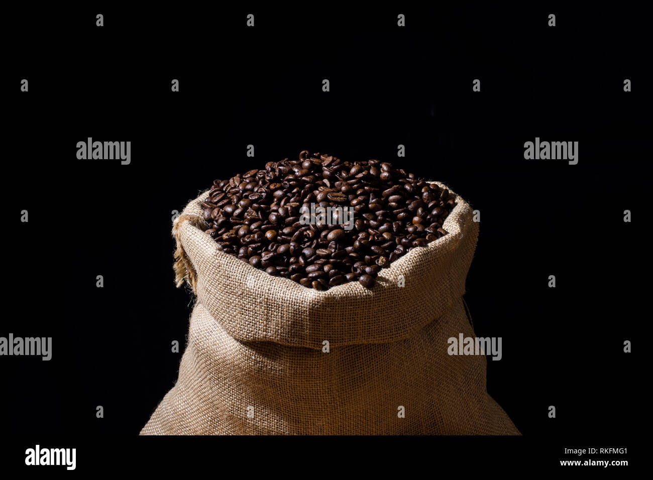 Close up de café torréfié dans une toile de jute sac en toile de jute et isolées en noir. Banque D'Images