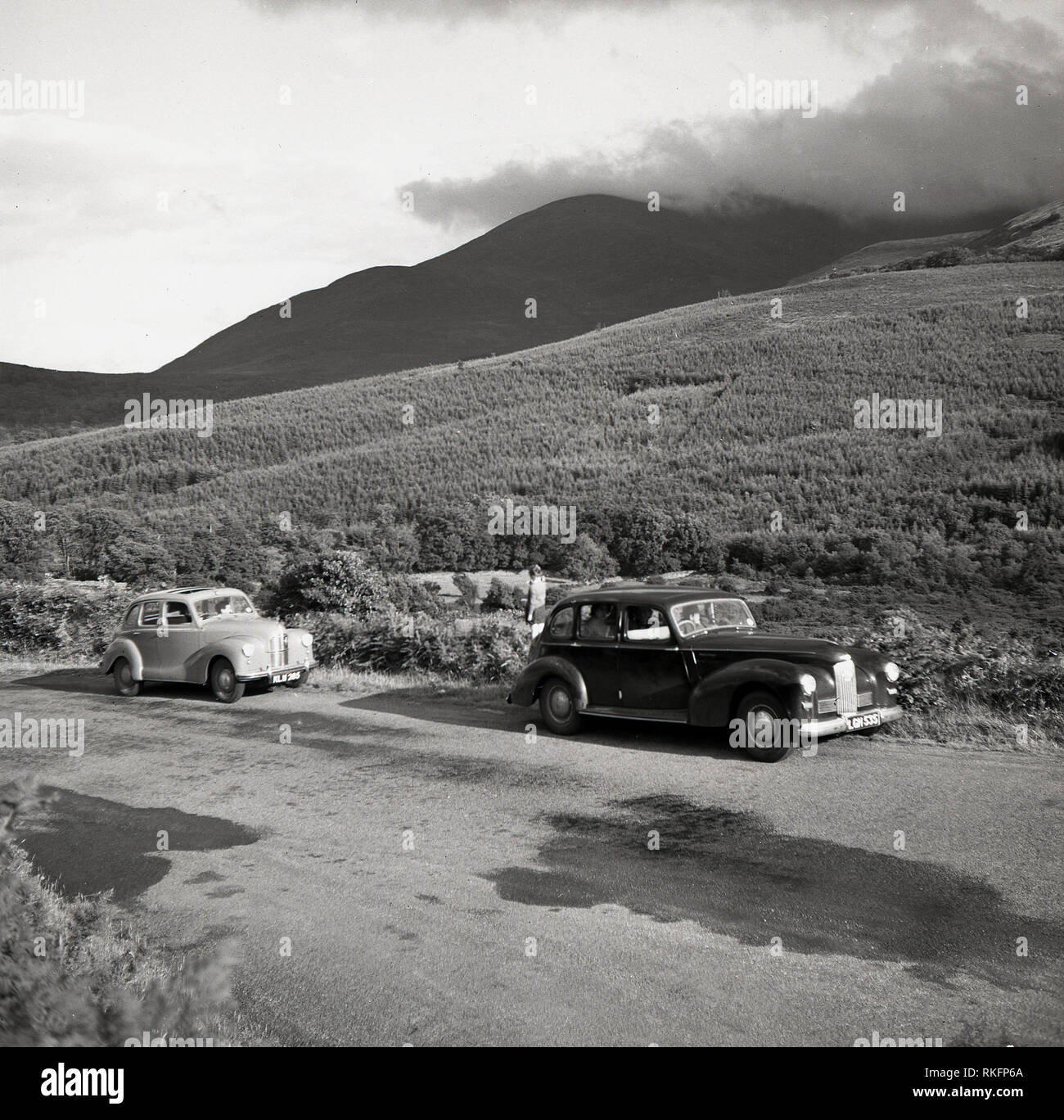 Années 1950, deux voitures de l'époque mis en garde sur une route de campagne Co. d'Antrim, en Irlande du Nord, dans les collines d'Antrim ou mountainsin l'arrière-plan. Banque D'Images