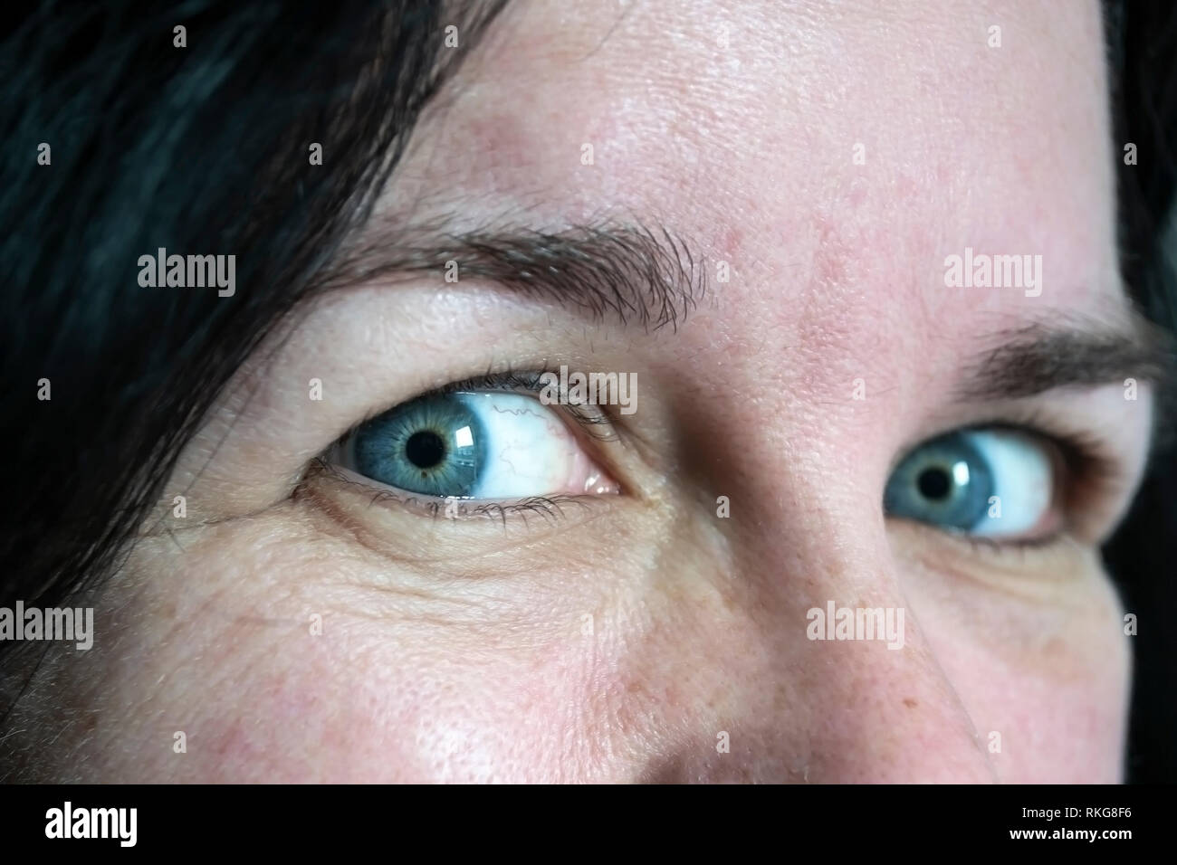 Close up of yeux bleus sur une femme de race blanche d'âge moyen à la recherche de l'appareil photo Banque D'Images