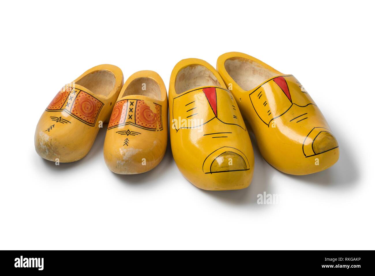 Deux paires de chaussures en bois traditionnel néerlandais jaune isolé sur fond blanc. Banque D'Images