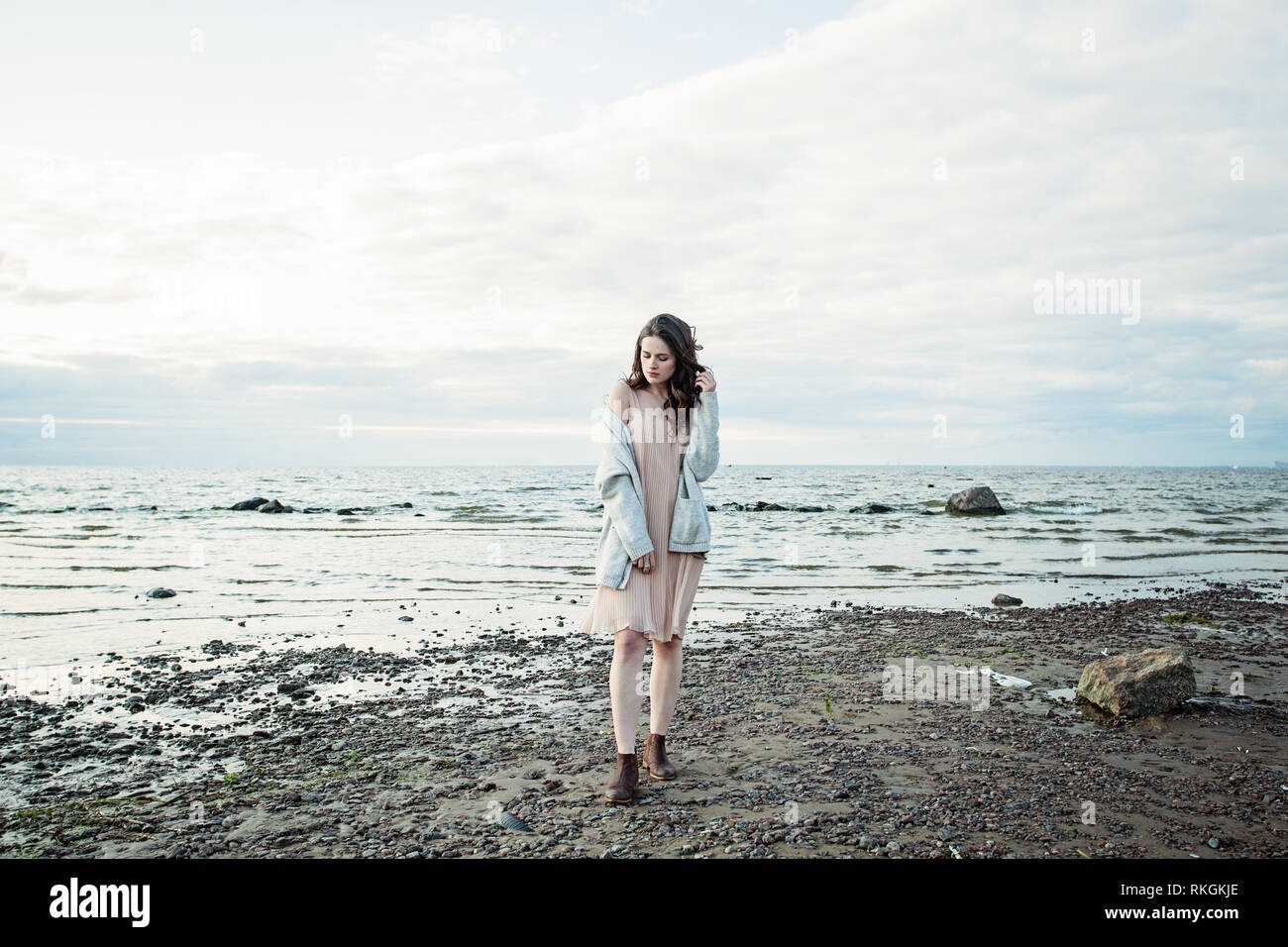 Beau modèle femme en robe de soie contre le ciel et la mer, portrait romantique Banque D'Images