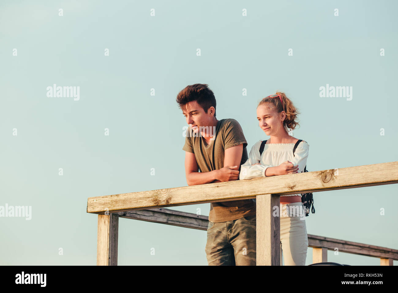 Happy smiling couple de jeune femme et homme assis sur un quai sur la mer durant les vacances d'été. Copie de texte Banque D'Images