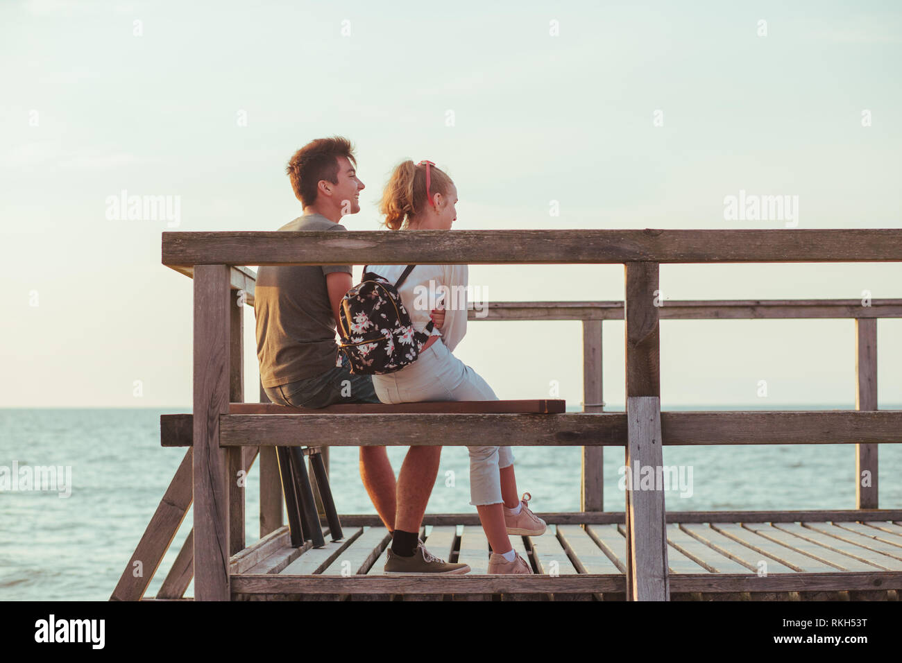 Happy smiling couple de jeune femme et homme assis sur un quai sur la mer durant les vacances d'été. Copie de texte Banque D'Images