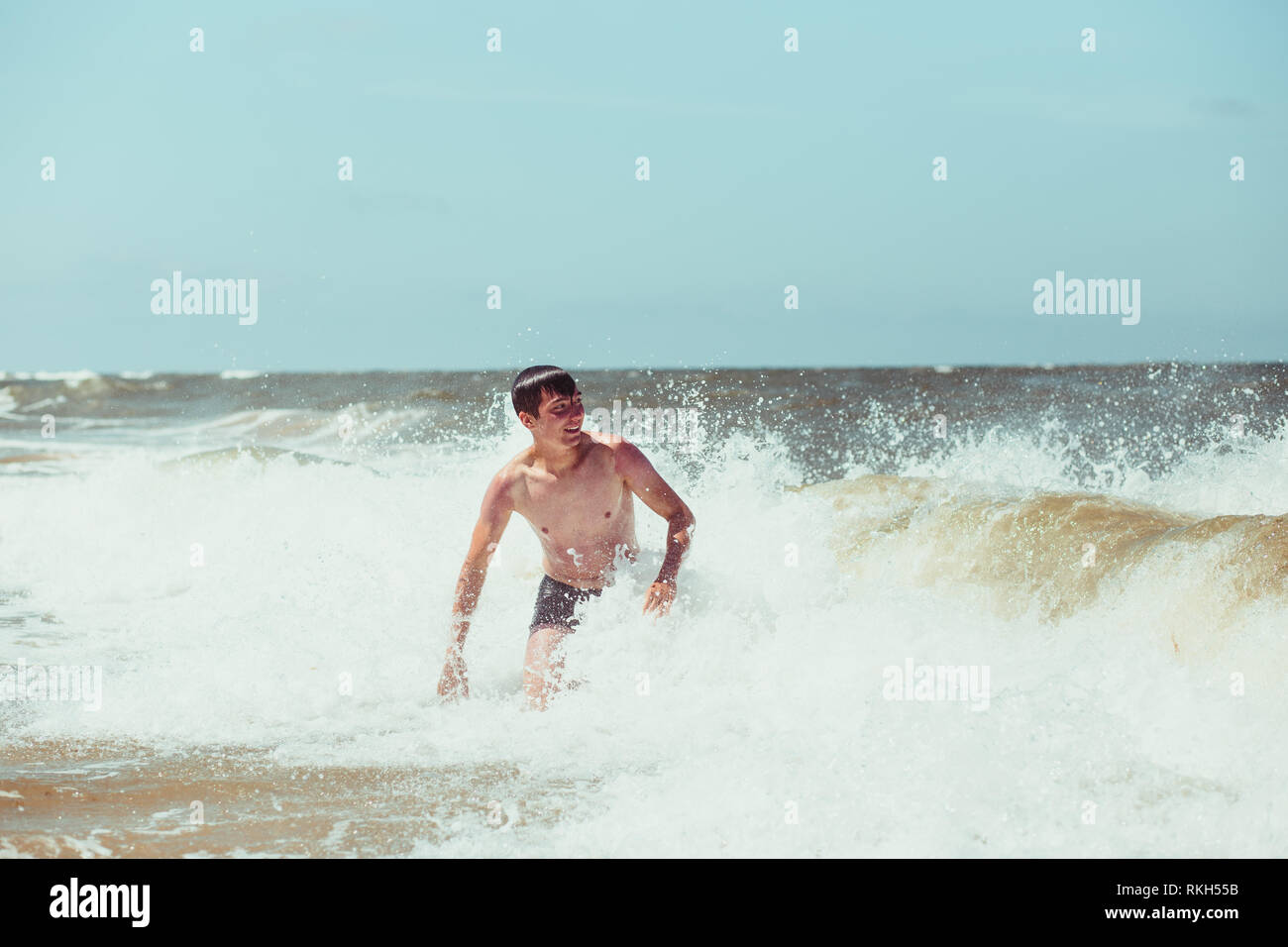 Jeune homme appréciant les vagues dans la mer lors d'une vacances d'été. Passer un des vacances à la mer Banque D'Images