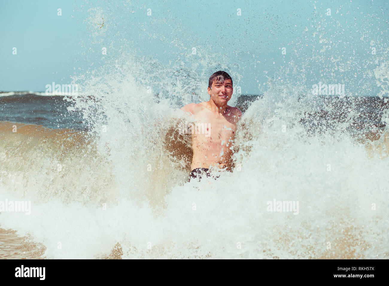 Jeune homme appréciant les vagues dans la mer lors d'une vacances d'été. Passer un des vacances à la mer Banque D'Images