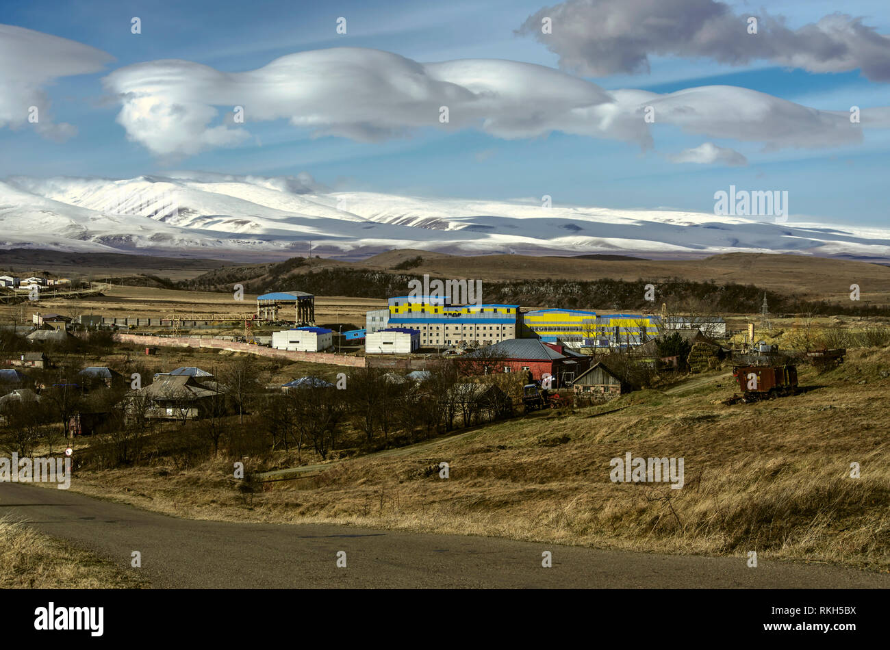 Après-midi d'hiver avec d'énormes nuages sur le ciel bleu ensoleillé sur un village de montagne avec enterprise dans la plaine de la montagnes neige-couvertes de Aragón Banque D'Images