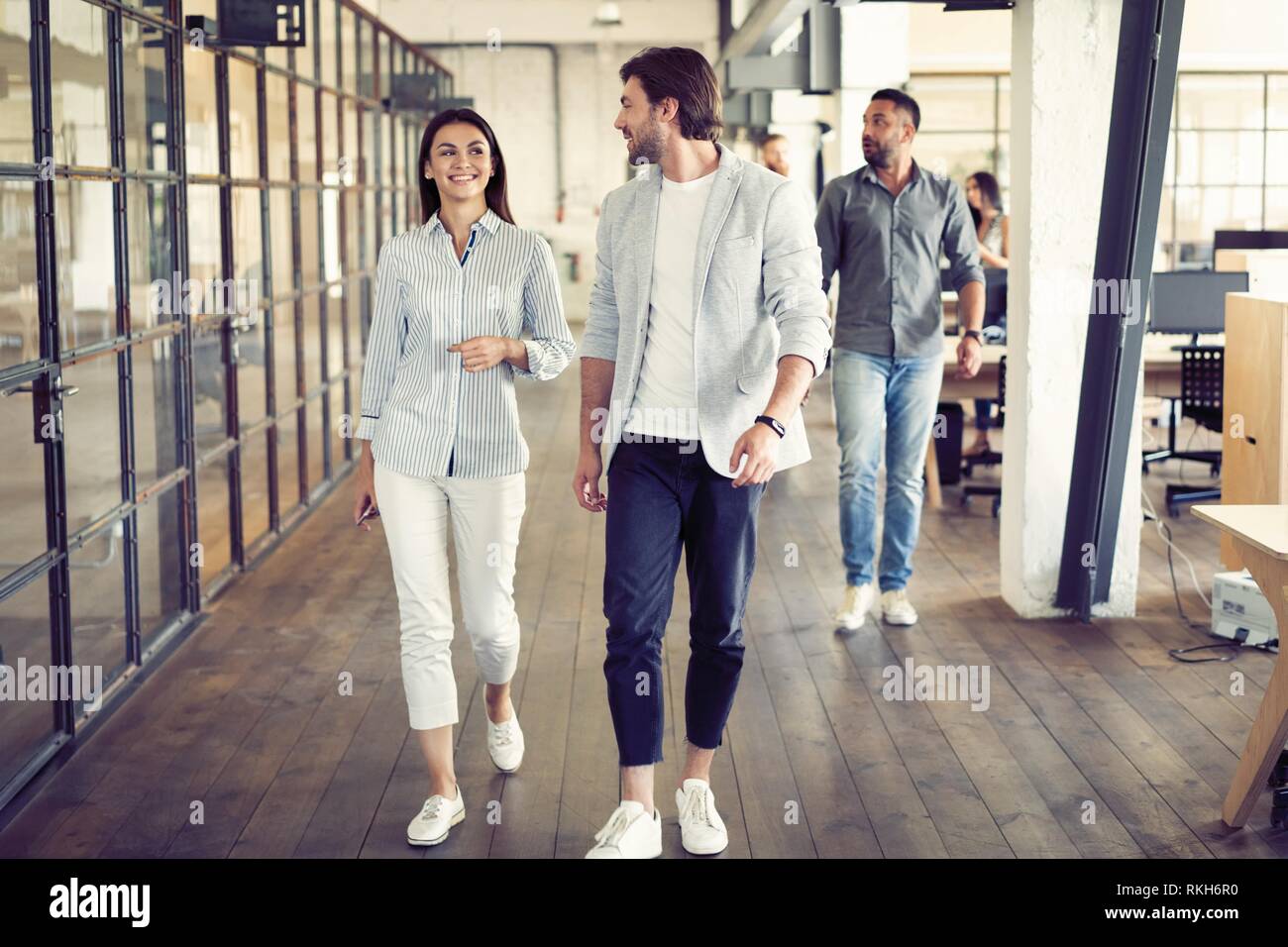 Sur le chemin à une réunion d'affaires. Longueur totale de jeunes gens  modernes dans smart casual wear ayant une discussion tout en marchant à  travers le bureau Photo Stock - Alamy