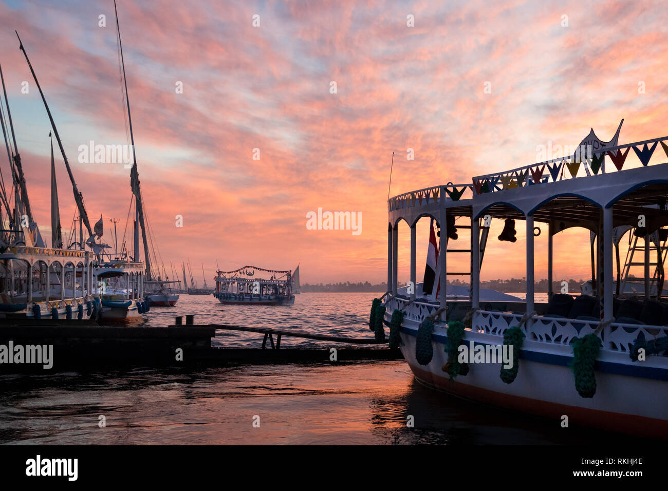 Différents bateaux au Nil à Louxor, Égypte, avec un beau coucher de soleil rose ciel dans l'arrière-plan Banque D'Images